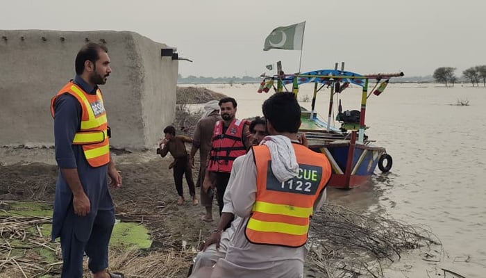 Rescue 1122 workers stand at the bank of a river amid relief operation in flood-hit areas of Khyber Pakhtunkhwa. — X@KPRescue1122