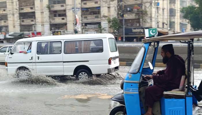 Commuters make way on an inundated road in Karachi after heavy rains on August 19, 2025. — Geo.tv