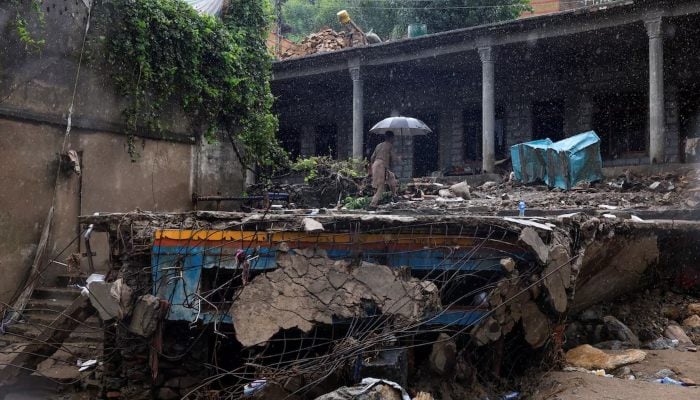 A resident walks with an umbrella to avoid rain at the damaged house, following a storm that caused heavy rains and flooding in Bayshonai Kalay, in Buner district, in Khyber Pakhtunkhwa province, August 18, 2025. — Reuters
