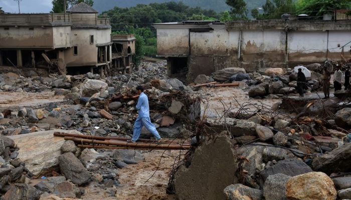 A resident walks on a makeshift crossway made of bamboo and wooden planks over rain water flowing from mountains crossing a damaged area, following a storm that caused heavy rains and flooding in Bayshonai Kalay, in Buner district, in Khyber Pakhtunkhwa province, August 18, 2025. — Reuters