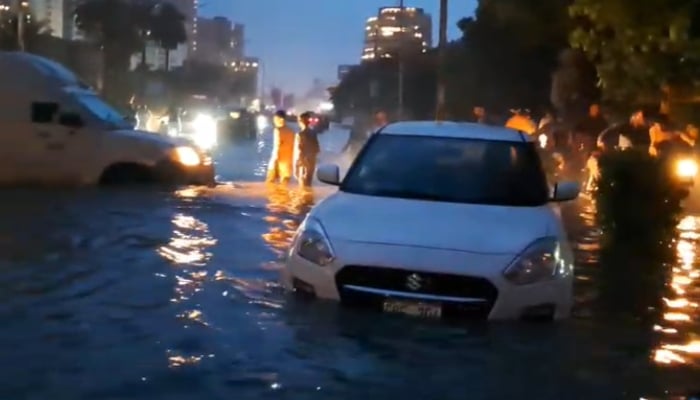 Partially submerged vehicles move after the monsoon rain in Karachi on August 19, 2025. — Geo News