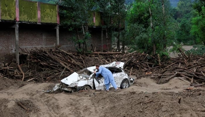 Gul Rasheed, 60, inspects a damaged car following a storm that caused heavy rains and flooding, in Bayshonai Kalay, Buner district, Khyber Pakhtunkhwa province, Pakistan. — Reuters