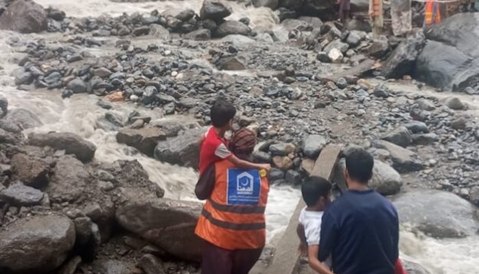 Rescuers carry children away from their flood-devastated village in the Buner region in Khyber Pakhtunkhwa. — Al Khidmat Foundation