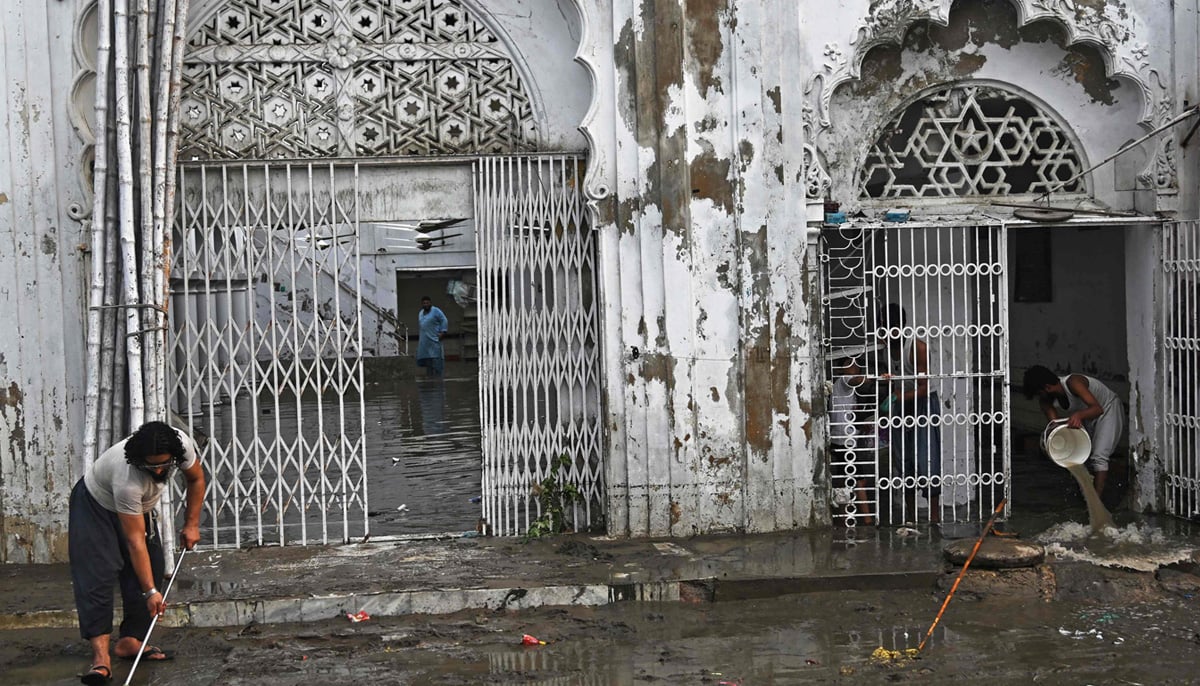 Workers clear the water from the flooded complex of a mosque after heavy monsoon rains in Karachi on August 20, 2025. — AFP