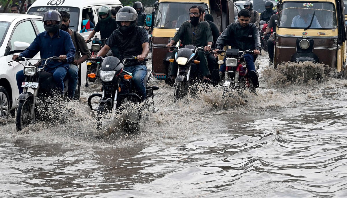 Commuters wade through a flooded street after heavy rainfall in Karachi on August 19, 2025. — AFP
