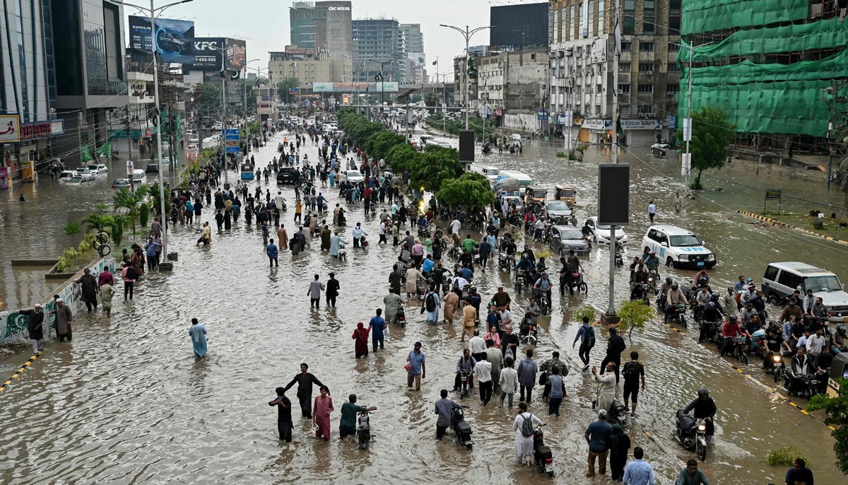People wade through a flooded street after heavy rainfall in Karachi on August 19, 2025. — AFP