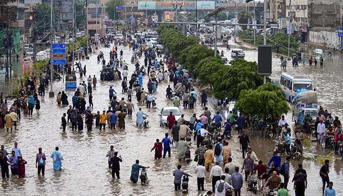 People wade through a flooded road after the monsoon rain in Karachi, August 19, 2025. — Reuters