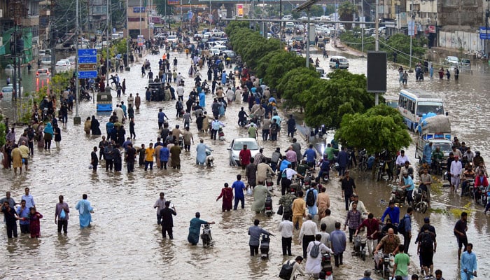 People wade through a flooded road after the monsoon rain in Karachi, Pakistan, August 19, 2025. — Reuters