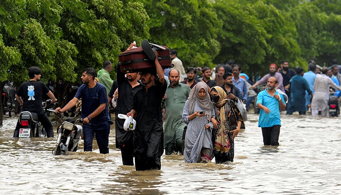 People wade through a flooded road after the monsoon rain in Karachi, August 19, 2025. — Reuters