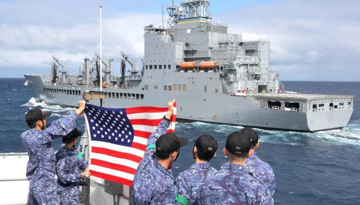 US Navy sailor are seen holding American flags, waving to USNS Harvey Milk in 2024.  — Reuters
