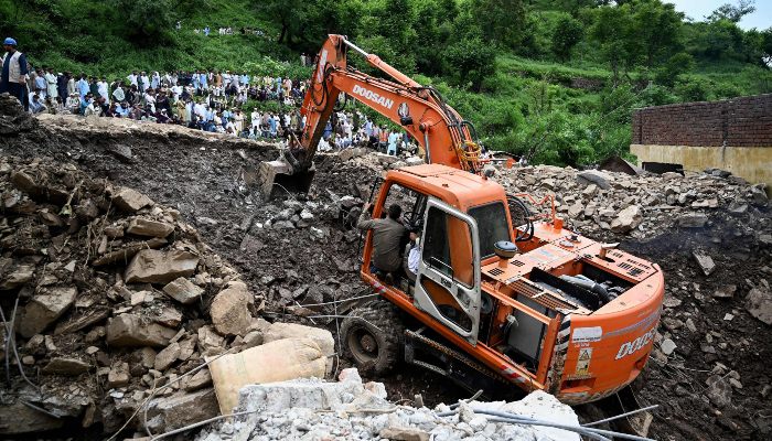 Relief personnel use an excavator to clear rubble of collapsed houses as they search through the debris for victims, a day after a cloudburst at the Dalori village in Swabi district, in KP on August 19, 2025. — AFP