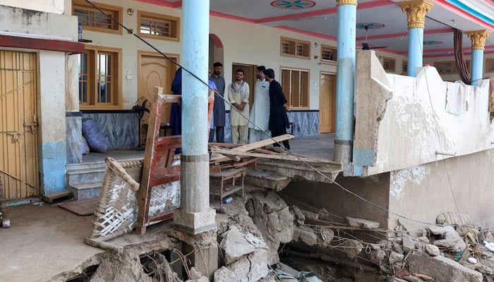 Noor Muhammad, 25, (3rd R) who lost 24 family members and relatives, stands at his damaged 36-room family house which was hit by devastating floods in the mountainous Qadir Nagar village of Buner district. — Reuters