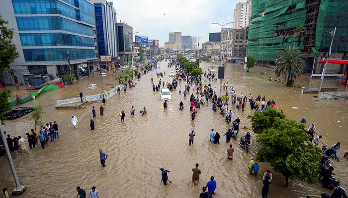 People wade through a flooded road after the monsoon rain in Karachi on August 19, 2025. — Reuters