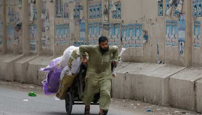 A labourer pulls a cart loaded with supplies to deliver to a nearby market in Karachi on May 24, 2023. — Reuters