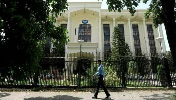 A policeman walks past the Federal Board of Revenue (FBR) office building in Islamabad, August 29, 2018. — Reuters