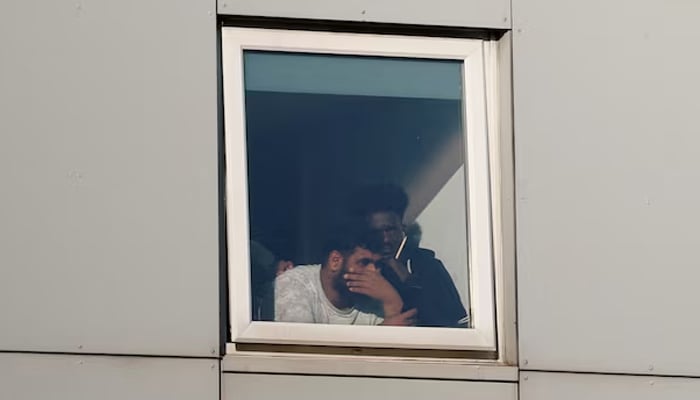 Asylum seekers react as they look out the window at the Cresta Court hotel, as people take part in an anti-immigration demonstration outside the hotel, in Altrincham, Britain, August 8, 2025. — Reuters