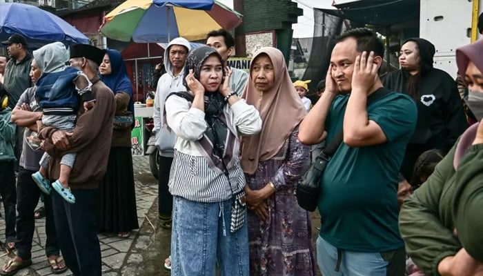 People cover their ears as a truck mounted with a tower of subwoofers drives past. — AFP/File