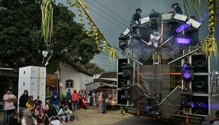Crew members sit atop a truck mounted with a tower of subwoofers used at Independence Day celebrations in Malang, East Java. — AFP