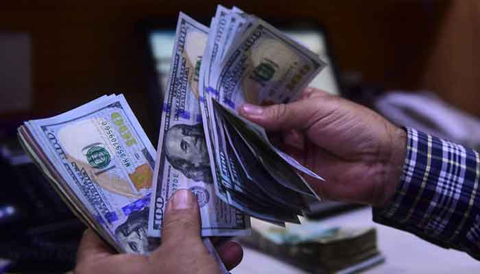 A dealer counts US dollars at a money exchange market in Karachi on March 2, 2023. — AFP