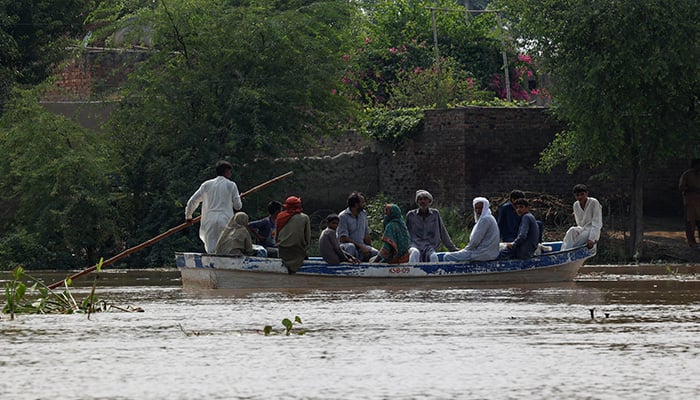 A resident carries milk buckets as he crosses a flooded road, due to the monsoon rains and rising water level of the Sutlej River, in Bhikhiwind village, near the Pakistan-India border in Kasur district of the Punjab, August 24, 2025.  — Reuters
