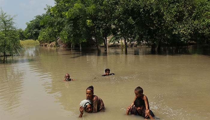 Villagers wade through a flooded street following heavy rains at the Ehsan Pur village in Kot Addu district, Punjab on August 21, 2025. — AFP