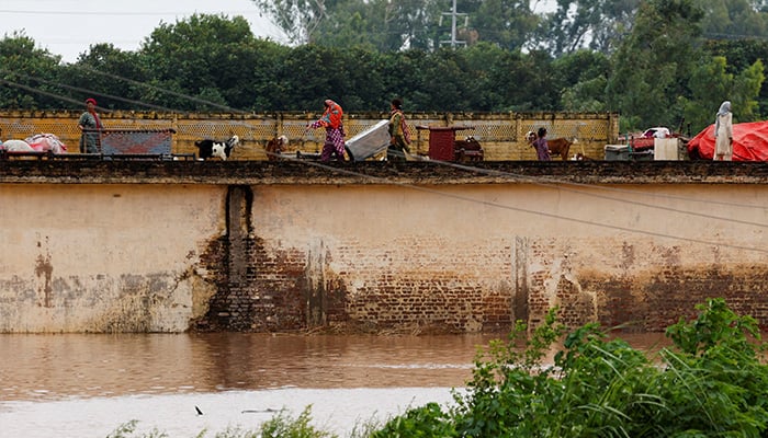A family with their belongings takes refuge over a roof of their house near Chenab River, following the monsoon rains and rising water level in Wazirabad, in Punjab, August 27, 2025. — Reuters