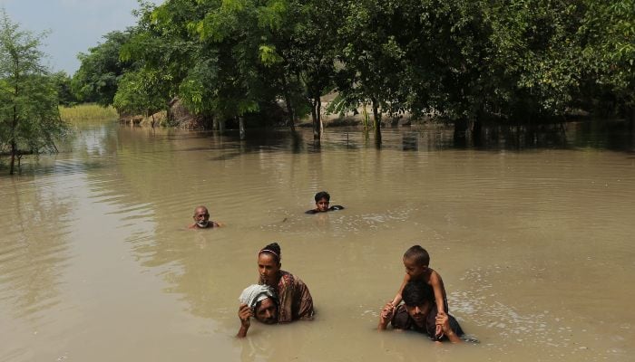 Villagers wade through a flooded street following heavy rains at the Ehsan Pur village in Kot Addu district, Punjab on August 21, 2025. — AFP