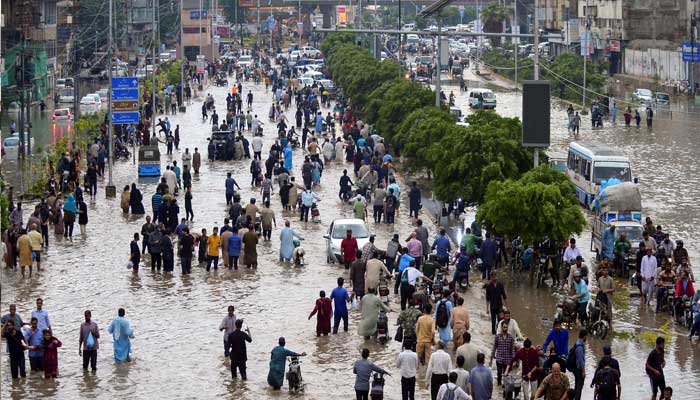 People wade through a flooded road after the monsoon rain in Karachi, August 19, 2025. — Reuters