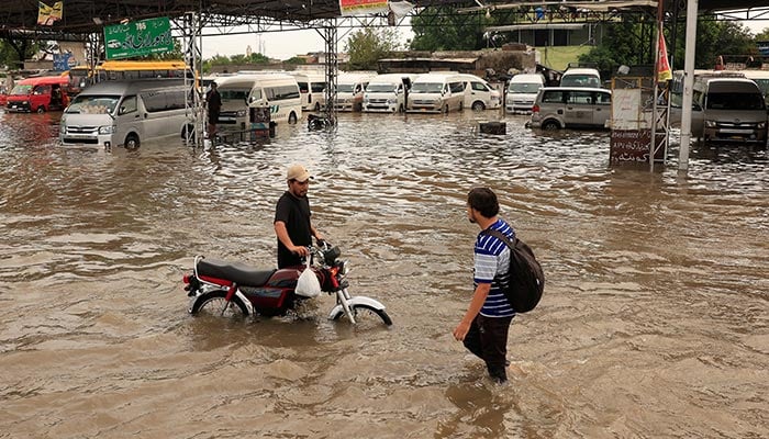 People walk past a partially flooded bus station following monsoon rains and rising water levels in Sialkot, on August 27, 2025. — Reuters