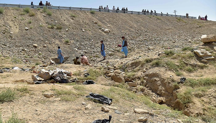 Afghans stand at the accident site, after a passenger bus overturned on the Kabul-Kandahar highway, on the outskirts of Maidan Wardak province on August 27, 2025. — AFP