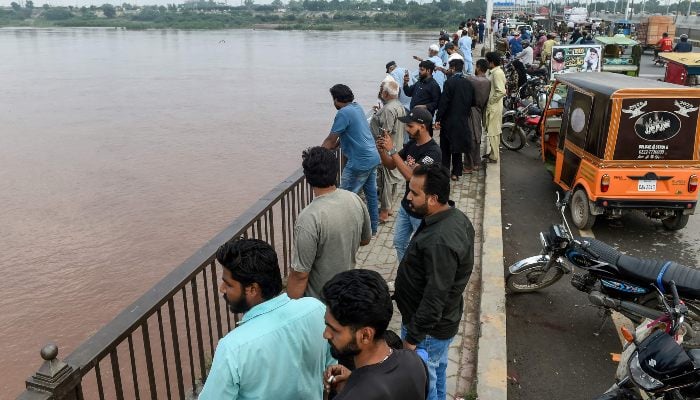 Commuters watch the Ravi River from a bridge as the government announced a flood alert in the riverside areas of Punjab, in Lahore on August 27, 2025. — AFP