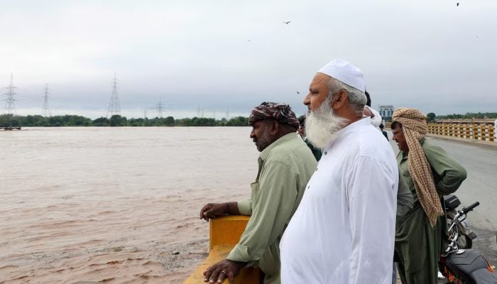 Men stand on a bridge over the Chenab River, following the monsoon rains and rising water level in Wazirabad, in Punjab, August 27, 2025. — Reuters