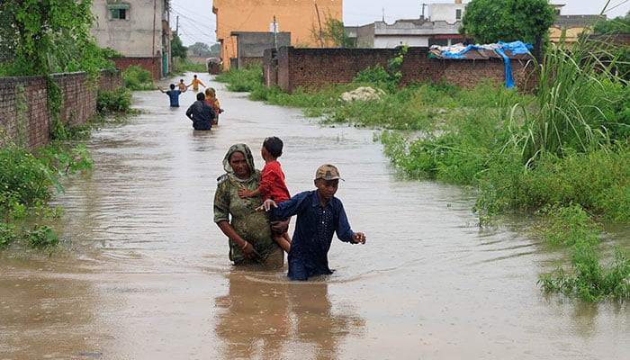 Residents wade through a flooded street, following monsoon rains and rising water levels in Punjabs Sialkot on August 27, 2025. — Reuters