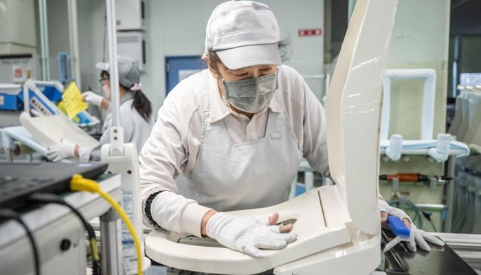 A worker at an assembly line of the Washlet Techno factory of Japanese toilet manufacturer TOTO. — AFP