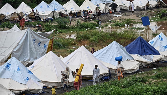 Flood-affected people walk along the shelters at a makeshift camp in Chung, in Punjab province, on August 31, 2025. — AFP