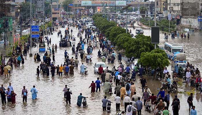 People wade through a flooded road after the monsoon rain in Karachi on August 19, 2025. — Reuters