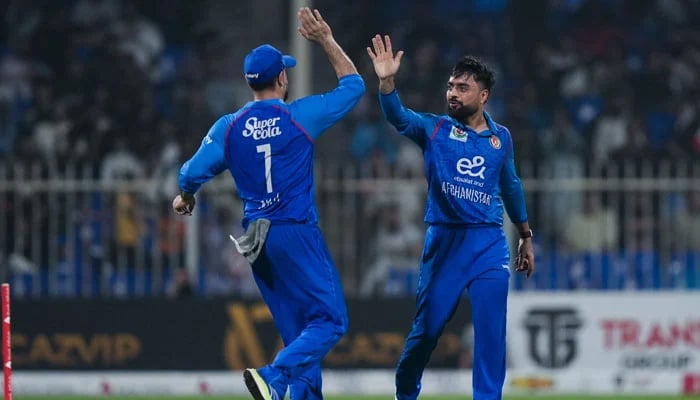 Afghanistans Rashid Khan (right) celebrates taking a wicket with Mohammad Nabi during their T20I tri-series match against Pakistan at the Sharjah Cricket Stadium in Sharjah on September 2, 2025. — Emirates Cricket Board