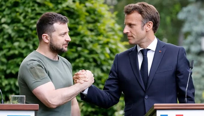 Ukrainian President Volodymyr Zelenskyy (L) and French President Emmanuel Macron shake hands after giving a press conference in at Mariinsky Palace in Kyiv, on June 16, 2022. — AFP