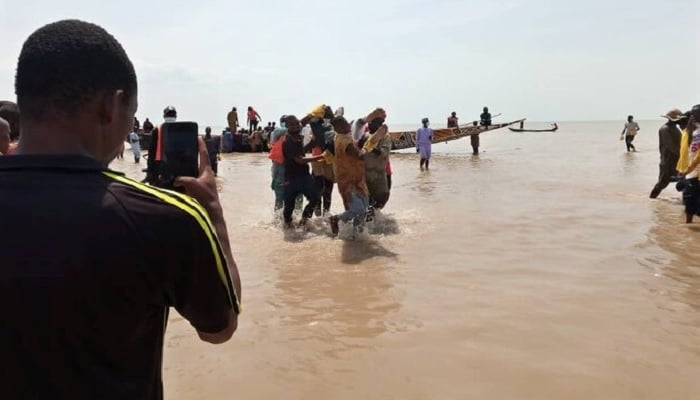 A man takes a picture as the body of one of the victims of a boat accident is being retrieved from the boat in Kebbi, Nigeria, May 27, 2021.— Reuters