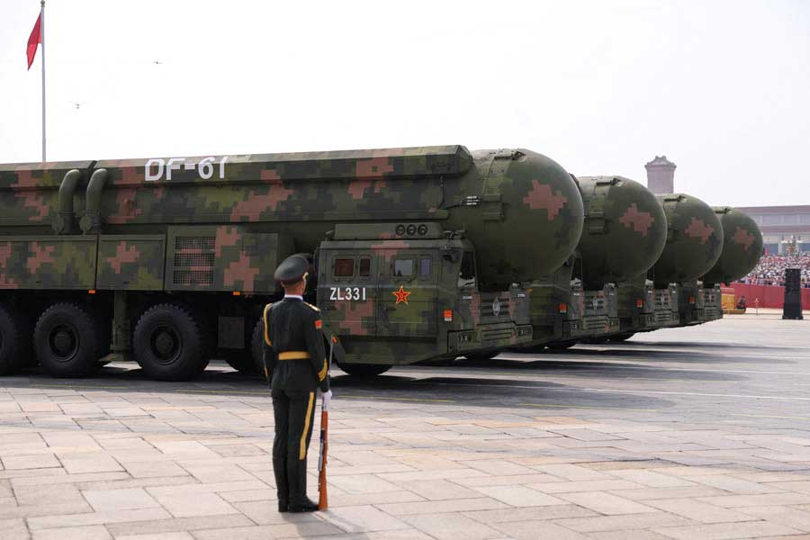 A member of the Peoples Liberation Army stands as the strategic strike group display DF-61 nuclear missiles. — Reuters