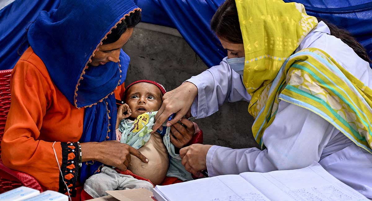 This photograph taken on July 29, 2025 shows a female doctor (R) examining a child during a UNICEF nutrition programme at Fateh Muhammad Soomro village in the Sujawal district of Sindh. — AFP