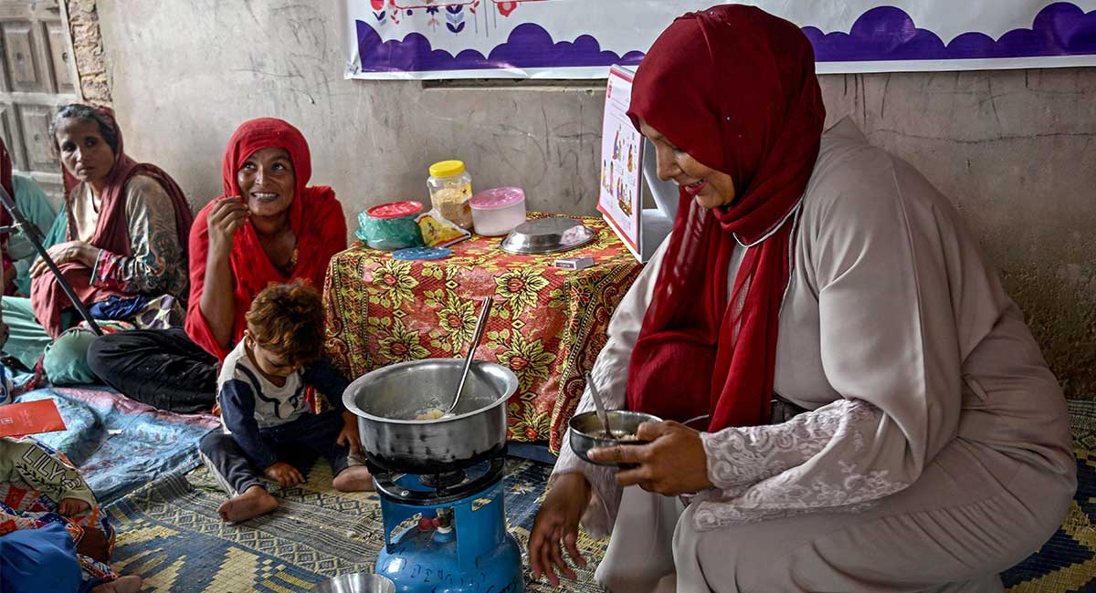 This photograph taken on July 29, 2025 shows a female health worker (R) teaching mothers how to prepare nutritious meals for their children during a UNICEF nutrition programme at Fateh Muhammad Soomro village in the Sujawal district of Sindh. — AFP