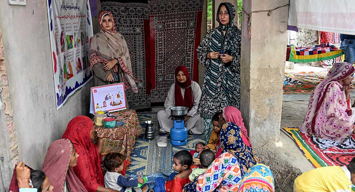This photograph taken on July 29, 2025 shows female health workers teaching mothers how to prepare nutritious meals for their children during a UNICEF nutrition programme at Fateh Muhammad Soomro village in the Sujawal district of Sindh. — AFP