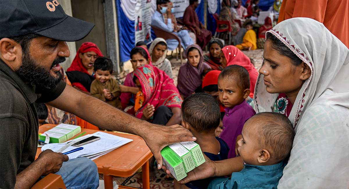 This photograph taken on July 29, 2025 shows a health worker (L) giving medicines after checking on children during a UNICEF nutrition programme at Fateh Muhammad Soomro village in the Sujawal district of Sindh. — AFP