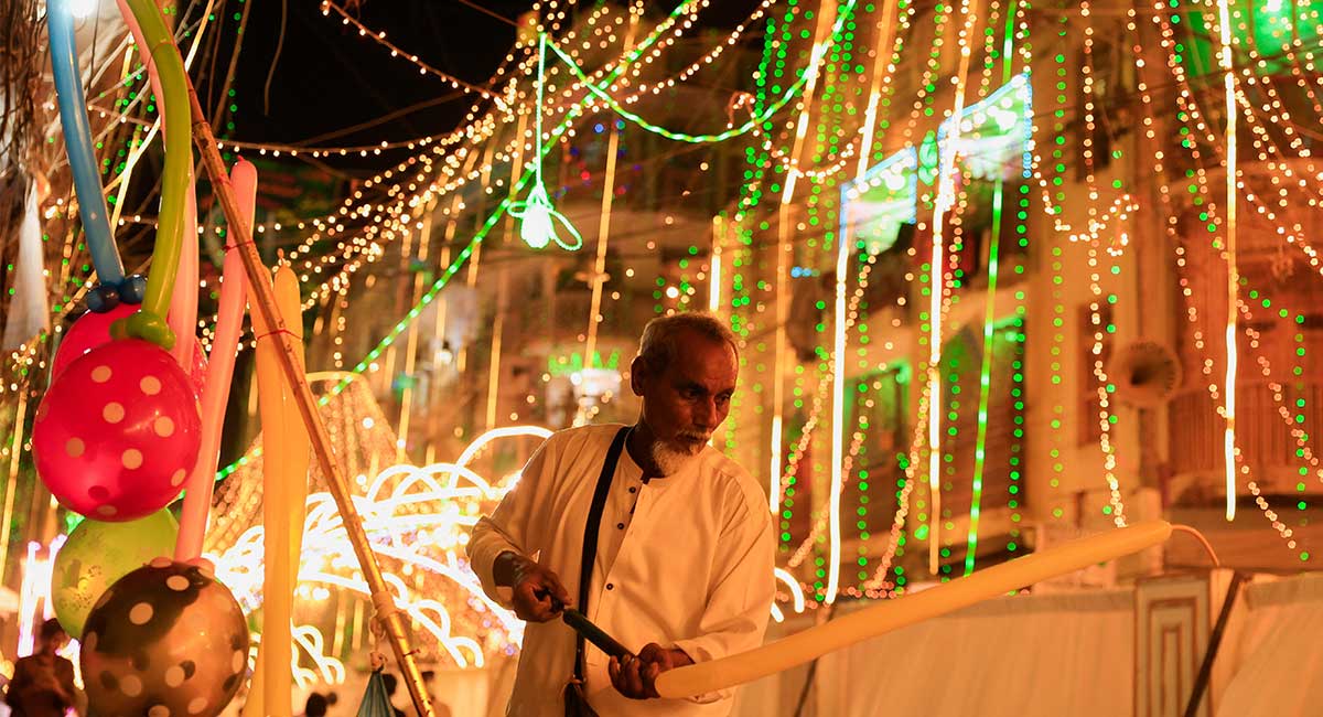 A man inflates a balloon while selling along an illuminated street ahead of Eid-e-Milad ul Nabi, the birth anniversary of Prophet Muhammad (PBUH), in Karachi, September 5, 2025. — Reuters
