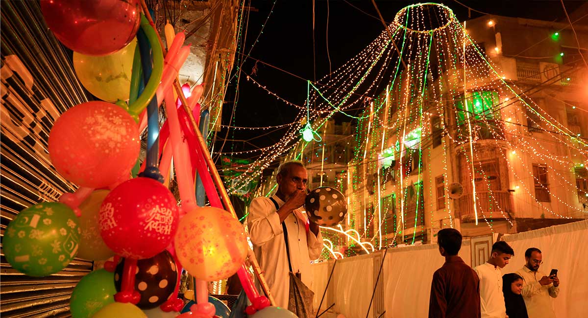 A man inflates a balloon while selling along an illuminated street ahead of Eid-e-Milad ul Nabi, the birth anniversary of Prophet Muhammad (PBUH), in Karachi, September 5, 2025. — Reuters
