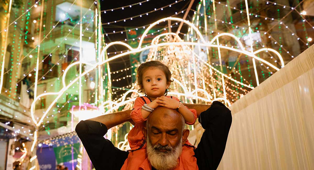 A girl sits on the shoulders of her grandfather as they visit an illuminated street ahead of Eid e Milad-ul-Nabi, the birth anniversary of Prophet Muhammad (PBUH), in Karachi, September 5, 2025. — Reuters