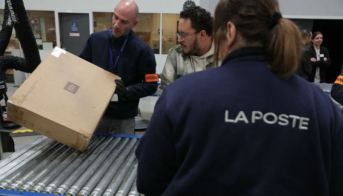 French Customs officers control postal parcels in the Customs area of the postal customs clearance office located in the sorting centre of La Poste, near Orly airport, South of Paris on March 20, 2025. — AFP