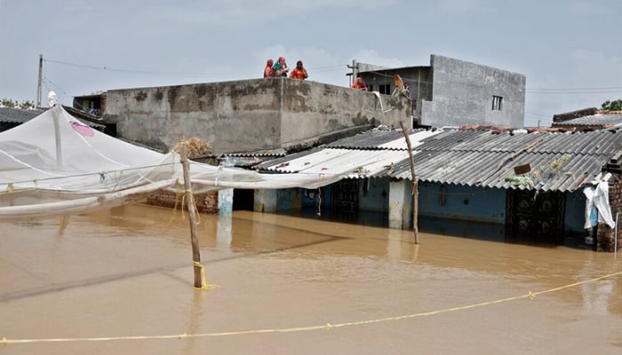 Residents stand on the rooftop of a submerged house in Kheda district of the western state of Gujarat, India, September 8, 2025. — Reuters