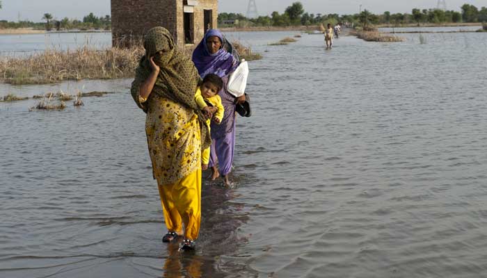 A family crosses the flooded streets in a village. — ADB/File